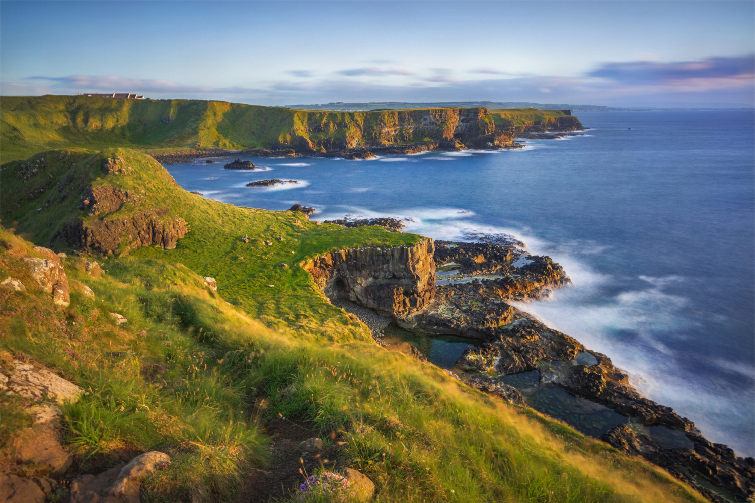 a rocky coastline with a body of water and grass
