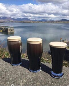 Golf Tours a group of glasses of beer on a ledge with a body of water in the background